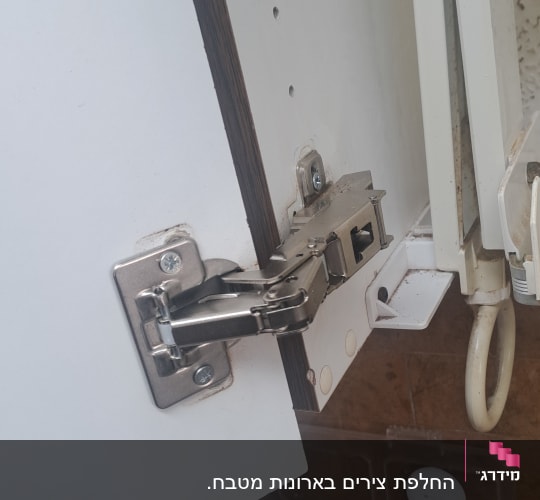 תקריב של ציר ארון מתכת עם מנגנון טריקה שקטה